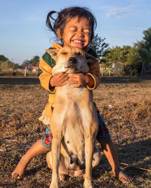 Une fillette serre son chien dans ses bras en plein air
